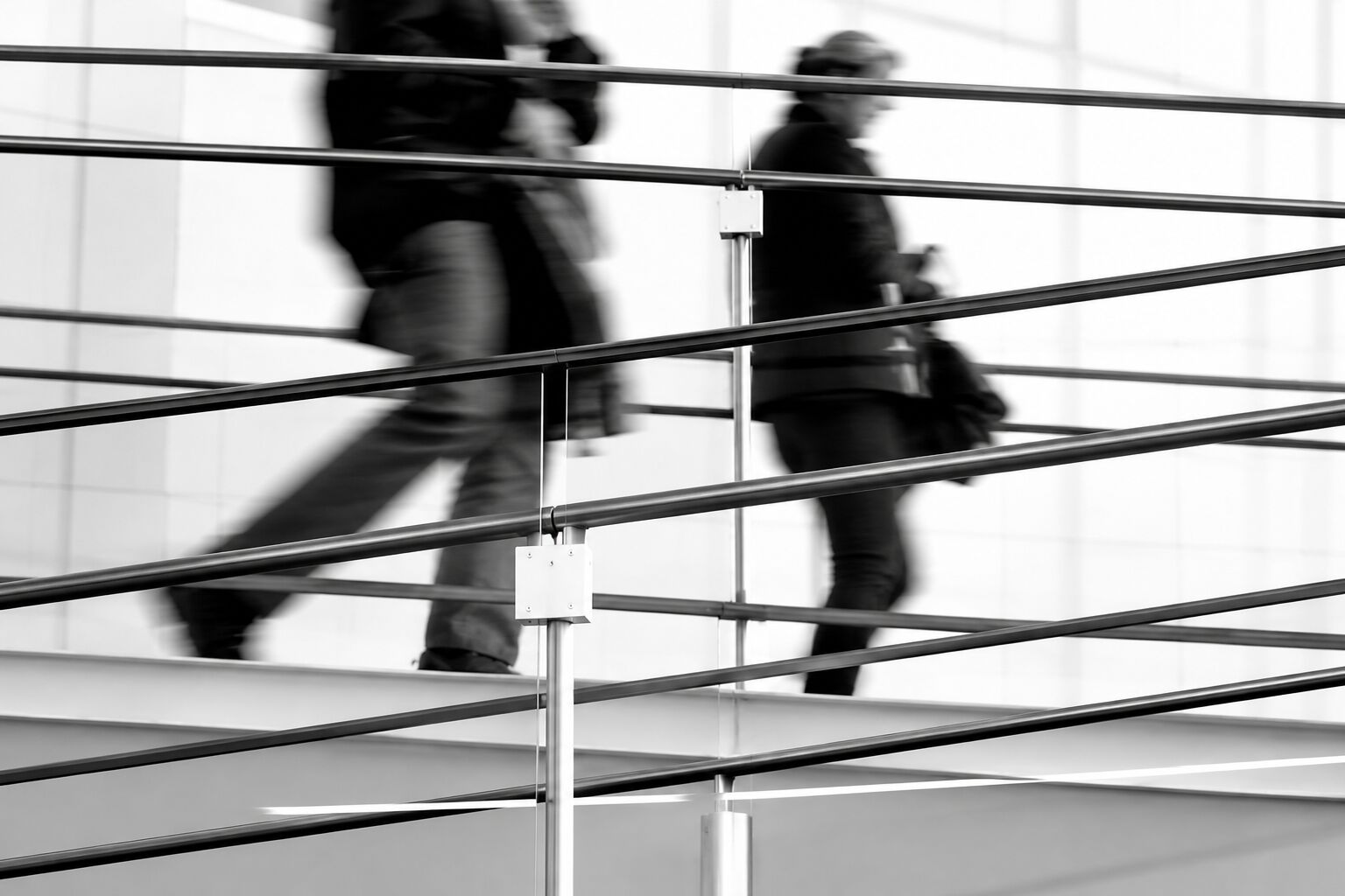 Figures moving along a stair rail in black and white