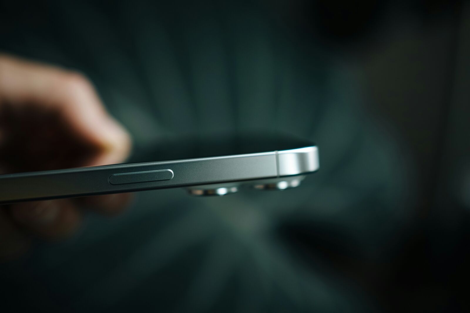 A phone in hand, lit against a dark teal background